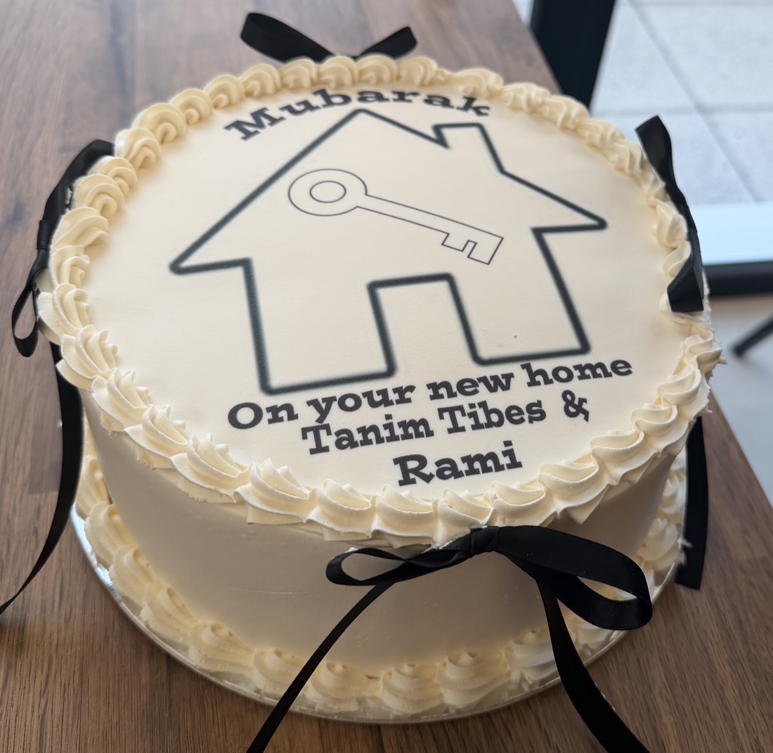 Ivory buttercream celebration cake with an edible new-home design and ribbon, by Cakes & Bakes Barkingside
