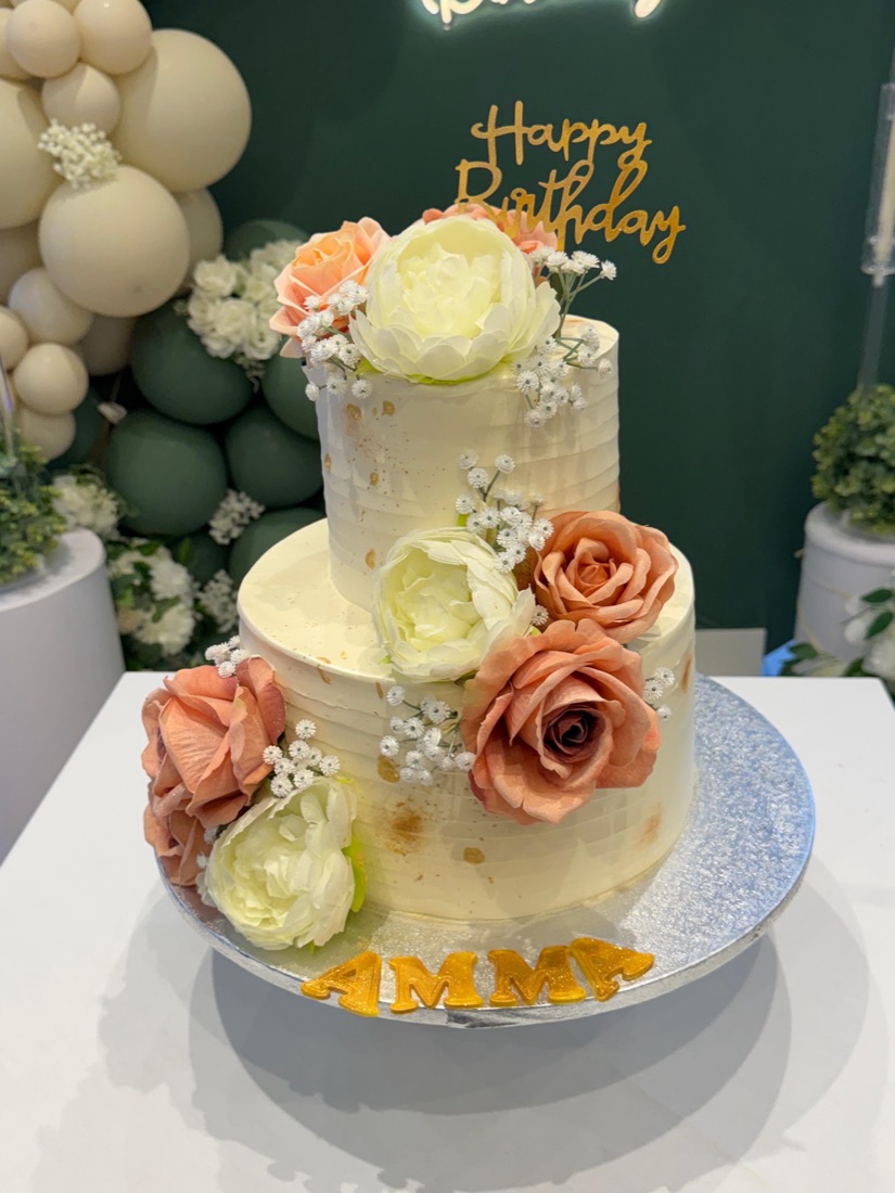 Two-tier ivory buttercream celebration cake dressed with roses, by Cakes & Bakes Barkingside