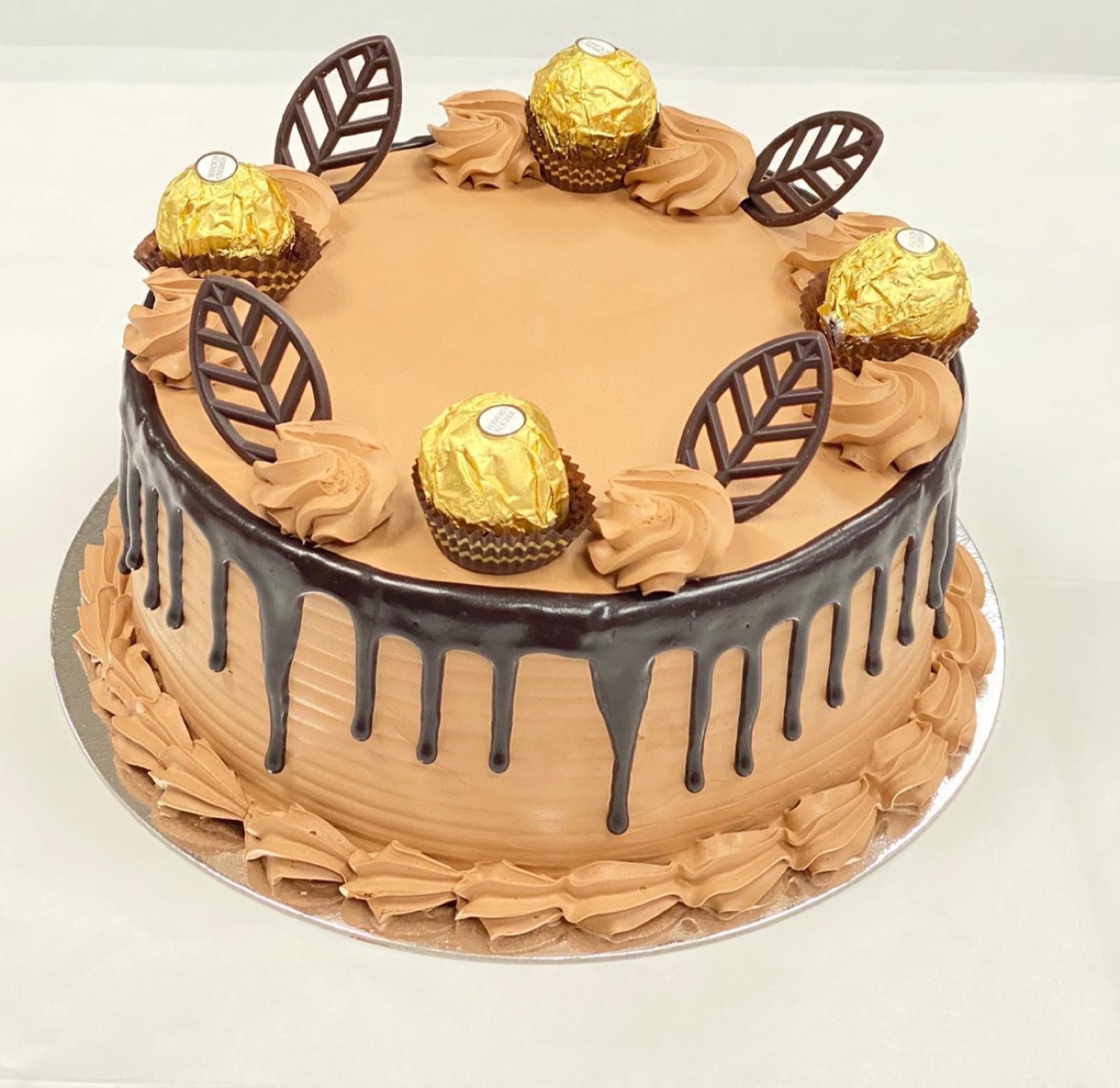 A chocolate fudge celebration cake with dark chocolate drip and Ferrero Rocher topping, made at Cakes & Bakes Barkingside